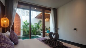 Une chambre d’hôtel avec un grand lit, une vue sur une piscine et un balcon agrémenté de plantes.