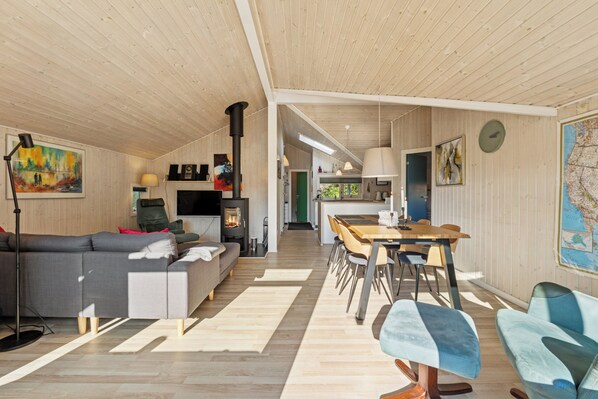 Un intérieur moderne avec un canapé, une table à manger, des chaises, un téléviseur et une carte accrochée au mur.