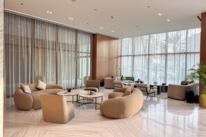 Ein geräumiger, moderner Lounge-Bereich mit bequemen Sitzgelegenheiten, großen Fenstern und einem glatten Boden.