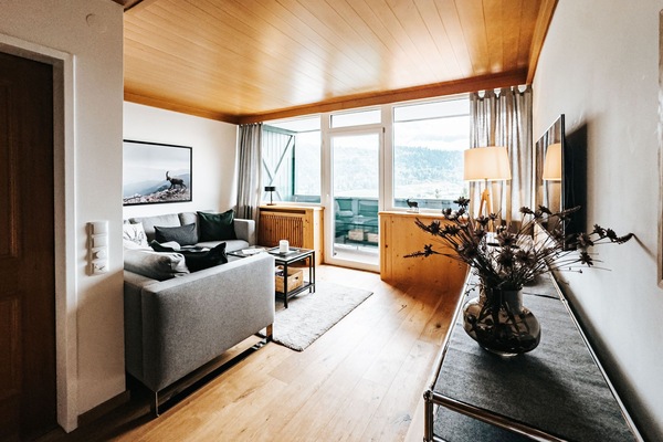 Wohnzimmer mit großem Sofa und Blick zum Dachstein durch das Panoramafenster.