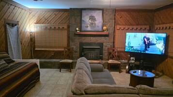 A cozy living room with a fireplace, a television, and a large sofa.