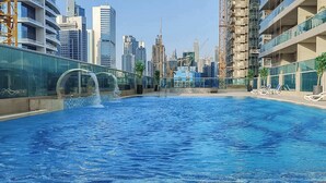Una piscina con sillas de descanso, rodeada de edificios modernos y grúas de construcción.