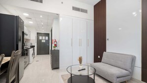 Una sala de estar moderna con un sofá gris, una mesa de centro de vidrio y un comedor con mesa y sillas.