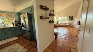 A kitchen with teal cabinets, a refrigerator, and a coffee maker. There is a dining area with a sofa and a table. The floor is tiled with terracotta tiles. - 3-bedroom house with Pool, Sauna in Ojai (Ojai)