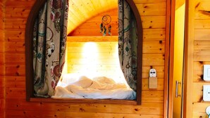 Ein gemütliches Blockhaus-Interieur mit einer hölzernen Bank, einem Tisch und einem Fenster mit Vorhängen.