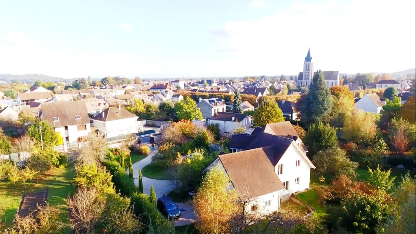 A residential area with houses, a church, and a hill in the background.