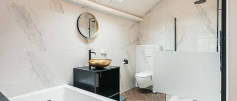 Une salle de bain moderne avec une baignoire sur pieds, un miroir rond et des toilettes.