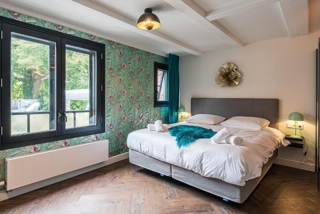 Ein Schlafzimmer mit einem Bett, einem Fenster, einer Wandleuchte und einem Wanddekor.