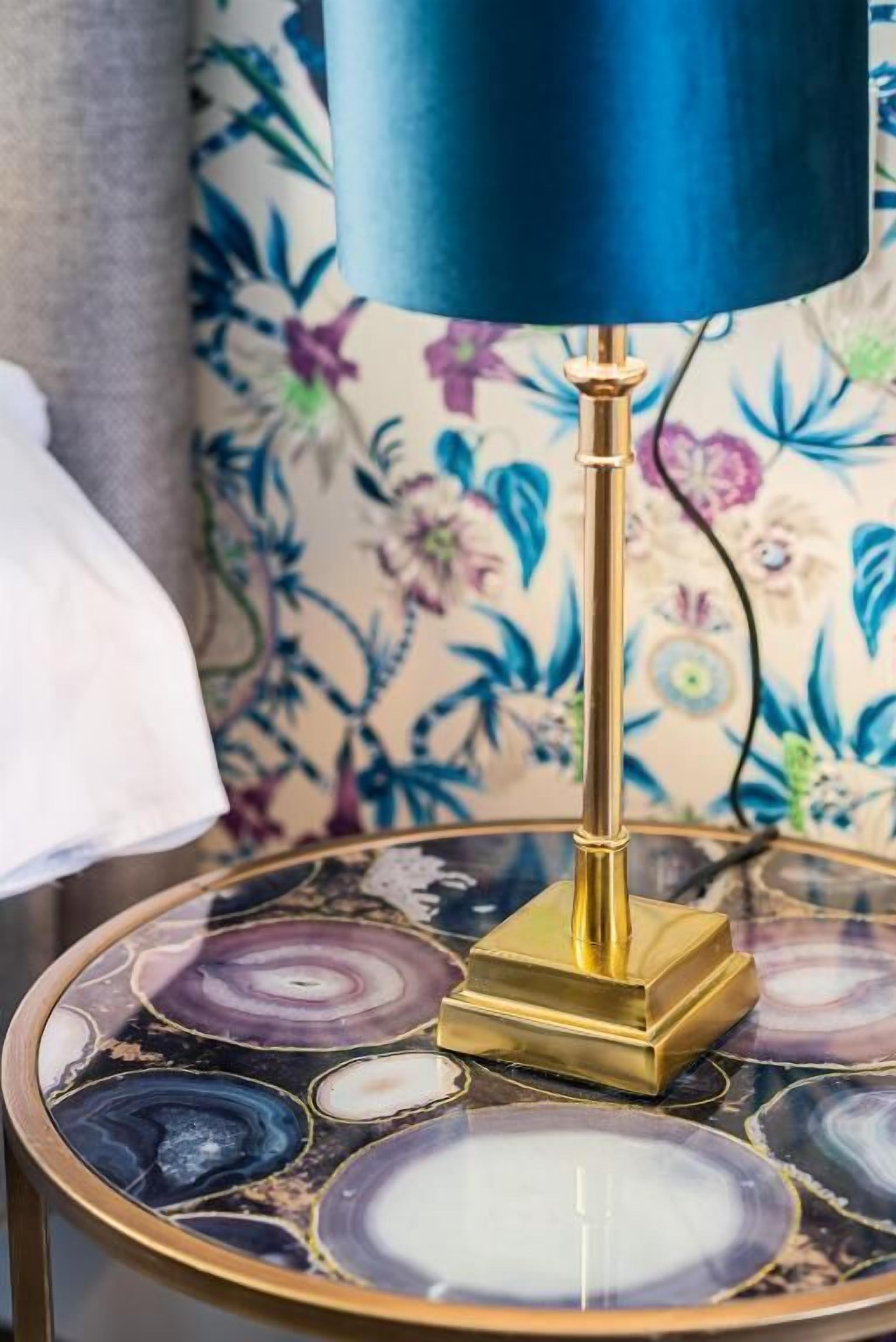 Una mesa con cubierta de vidrio decorativa que presenta diseños circulares y una base de latón.