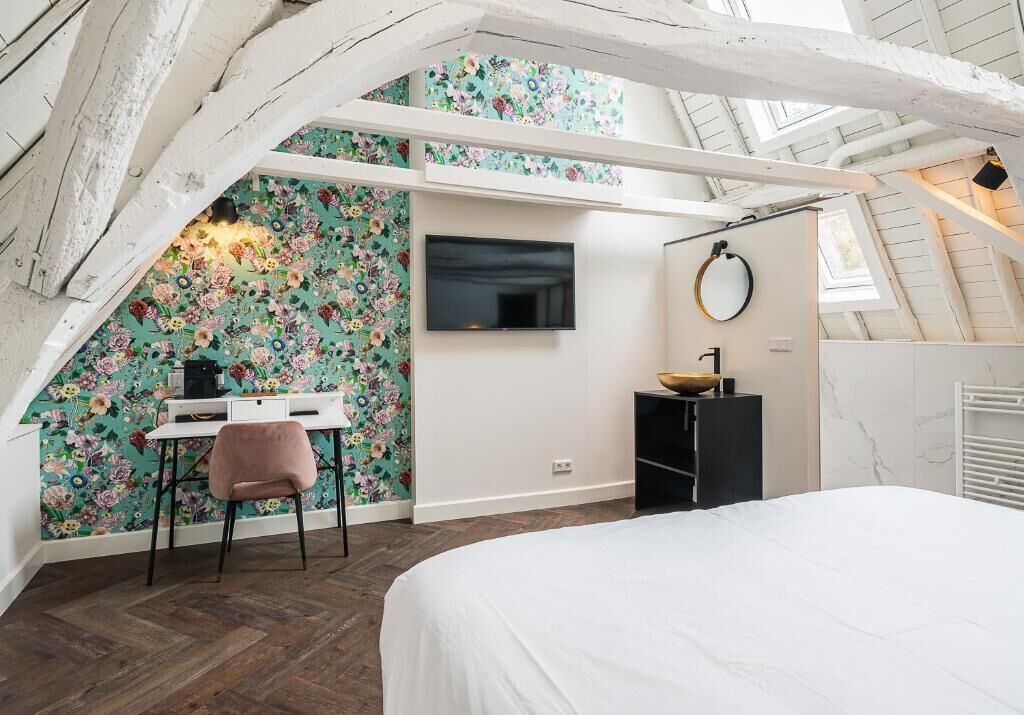 Ein Schlafzimmer mit Bett, Schreibtisch mit Stuhl, Fernseher und einem Badezimmer mit Spiegel und Waschbecken.