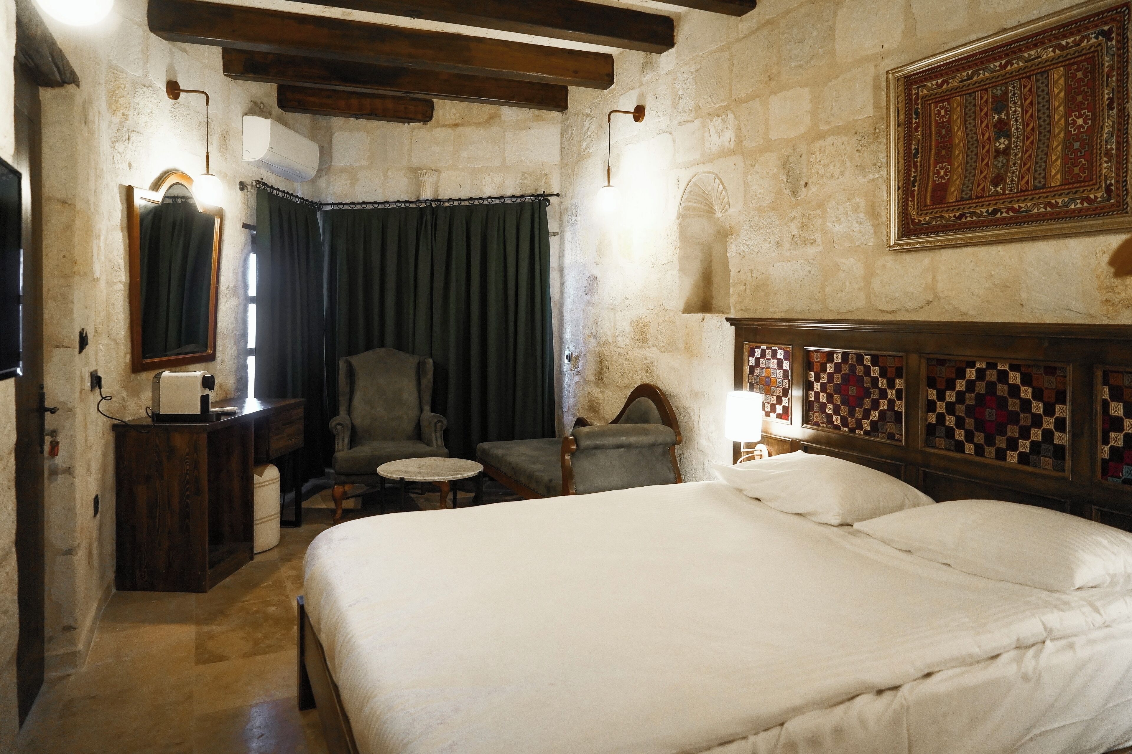 A bedroom with a large bed, a chair, a small table, and a mirror.