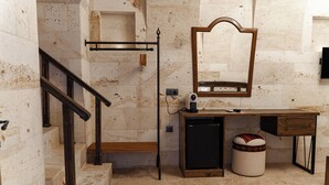 Ein Badezimmer mit Marmorwand, einer Holzbank, einem Spiegel, einem Waschbecken und einem kleinen Hocker.