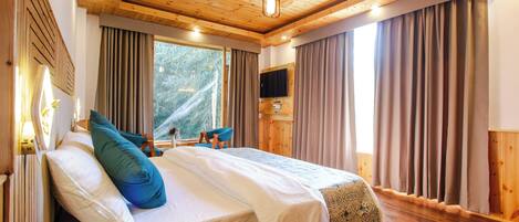 A wooden-paneled bedroom with a bed, curtains, a television, and a window.