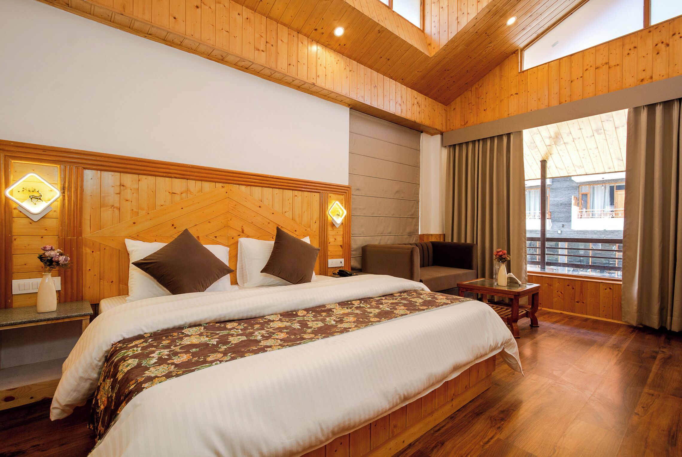 A wooden-paneled bedroom with a large bed, a TV, and a window with curtains.