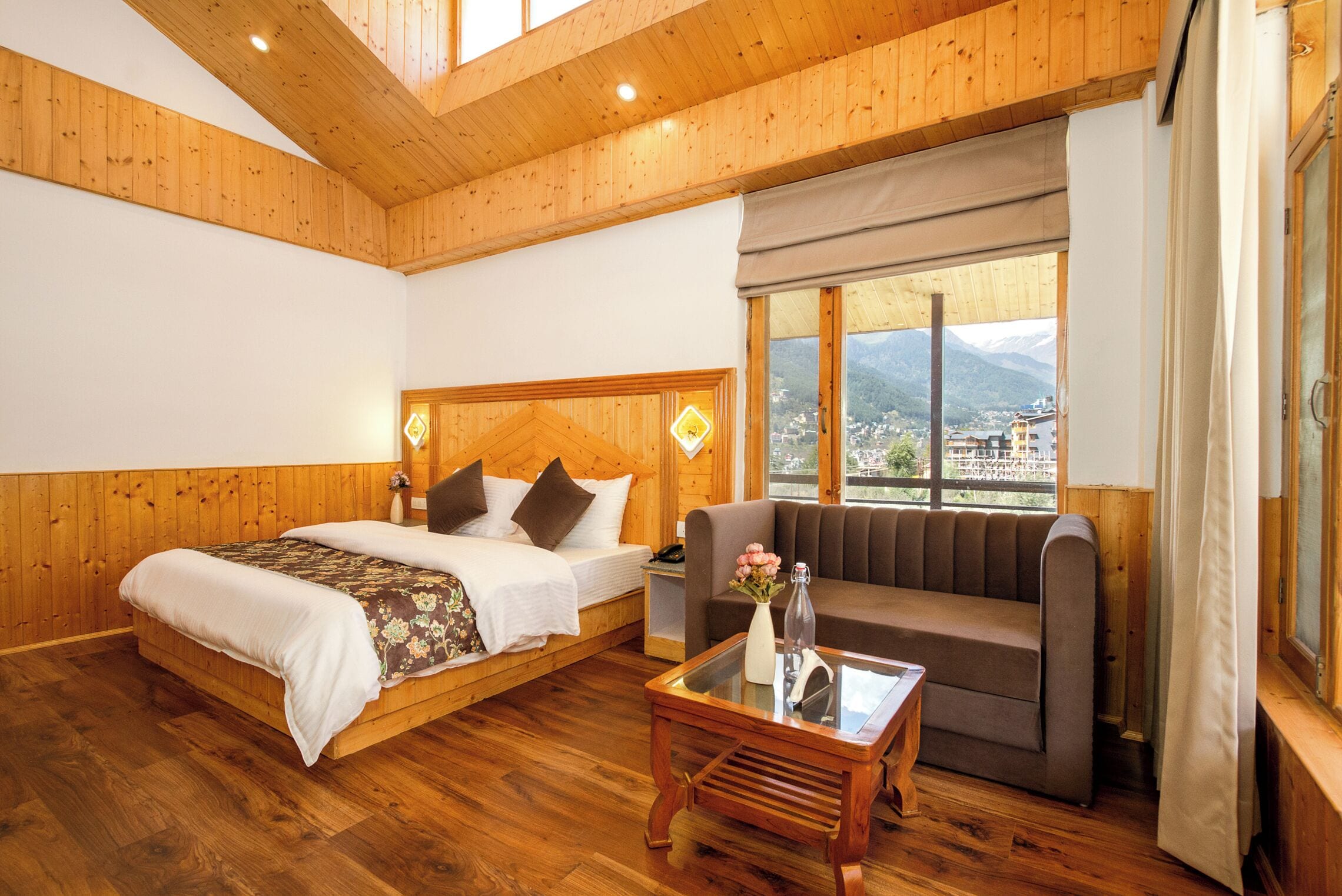 A wooden-paneled room with a bed, sofa, and a table.