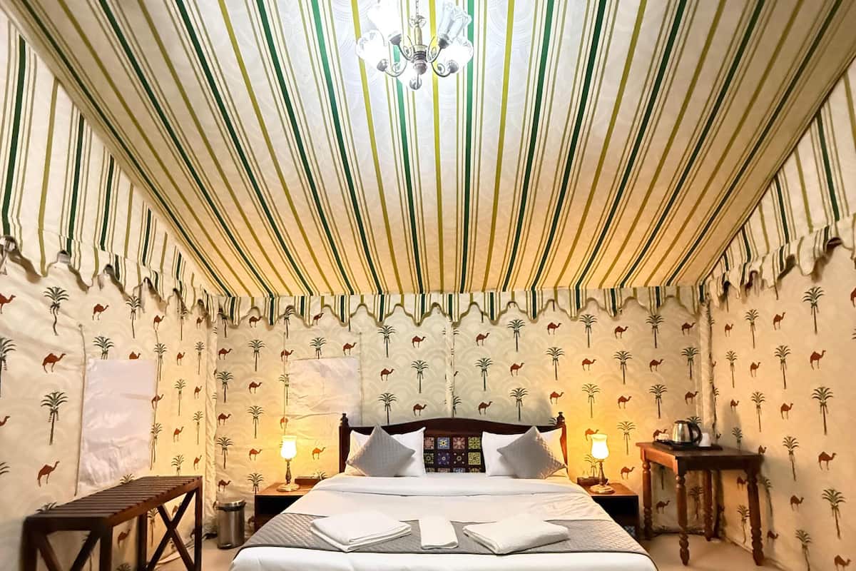 Una stanza con un letto grande, carta da parati a righe e una testiera decorata.