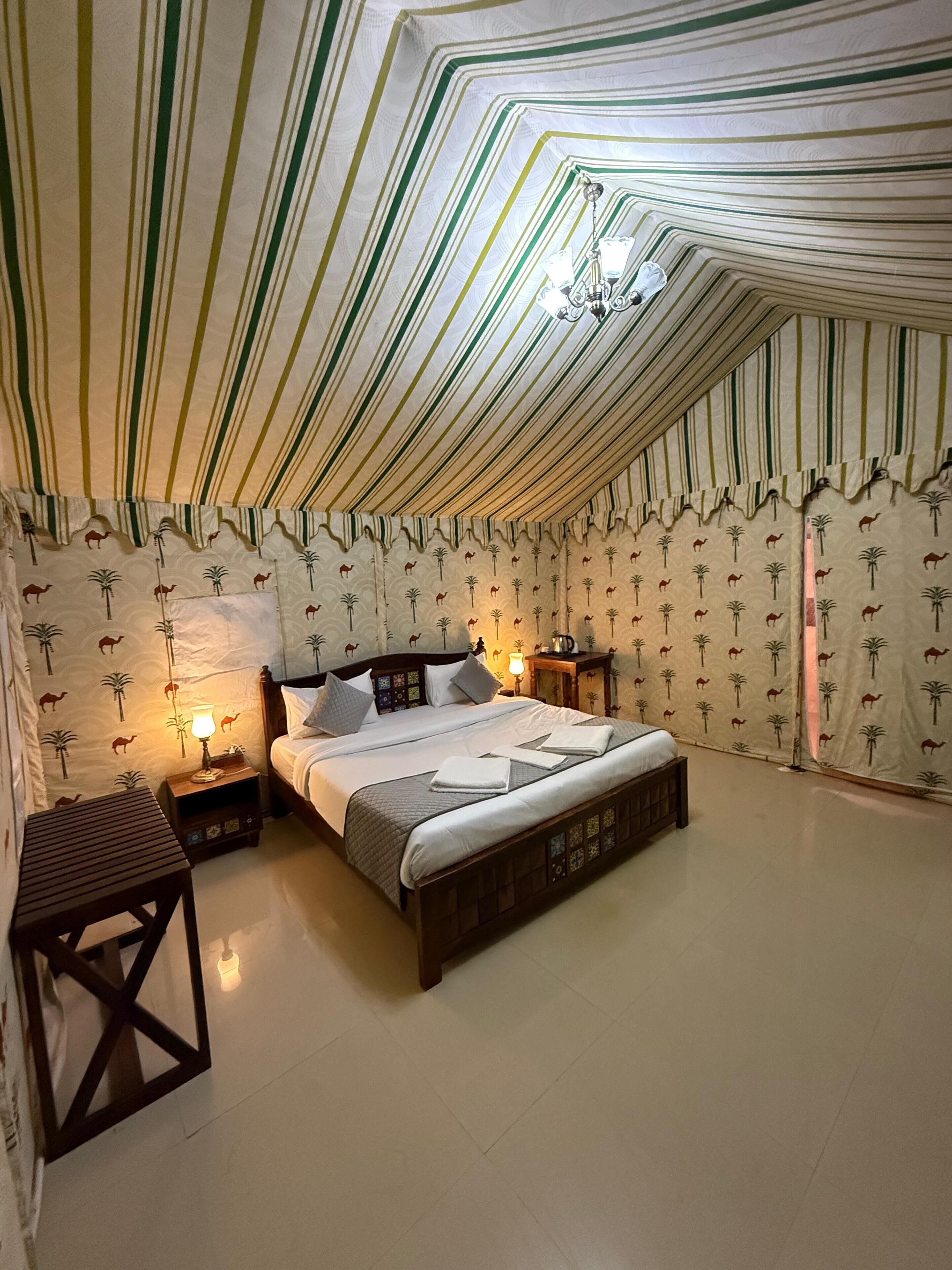A tented room with a bed, nightstands, and a table.