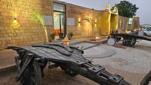 Un edificio con fachada de ladrillo, un acceso amplio y un patio con un vehículo y elementos decorativos.