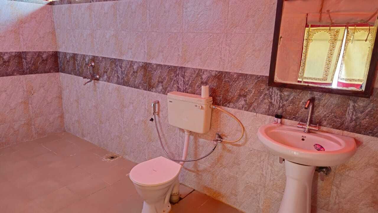 A bathroom with a toilet, a sink, and a marble-tiled wall.