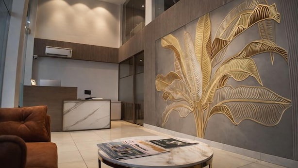 Un hall d’entrée moderne avec un comptoir de réception, un sol recouvert de carreaux de marbre et un grand panneau mural décoratif.