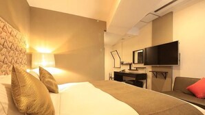 Una habitación de hotel con cama, escritorio, televisor y sofá.