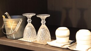 Una estantería con un cuenco negro, dos candelabros de vidrio y dos platos blancos con cubiertos.