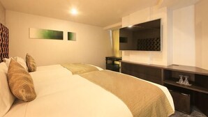 Habitación de hotel con dos camas, televisión, escritorio y espejo.