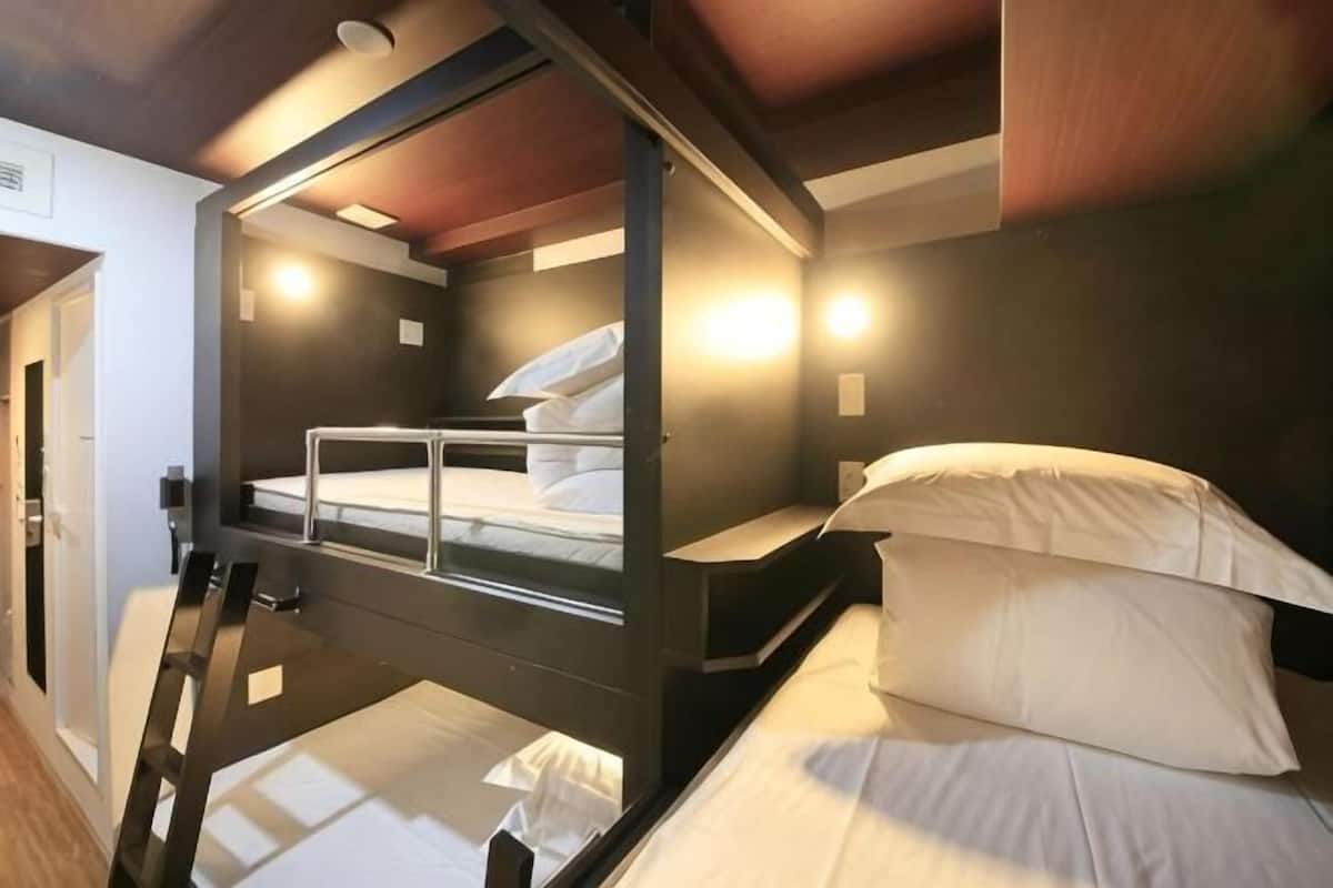 A bunk bed room with a ladder, a door, and a wall-mounted light fixture.