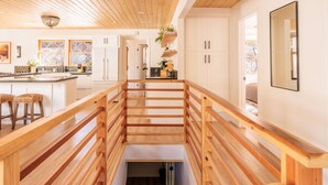 Une cuisine moderne avec des éléments en bois, des meubles blancs et un îlot central doté de tabourets.