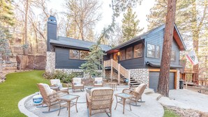 Une maison moderne avec des fondations en pierre, une terrasse en bois et une cheminée en pierre.