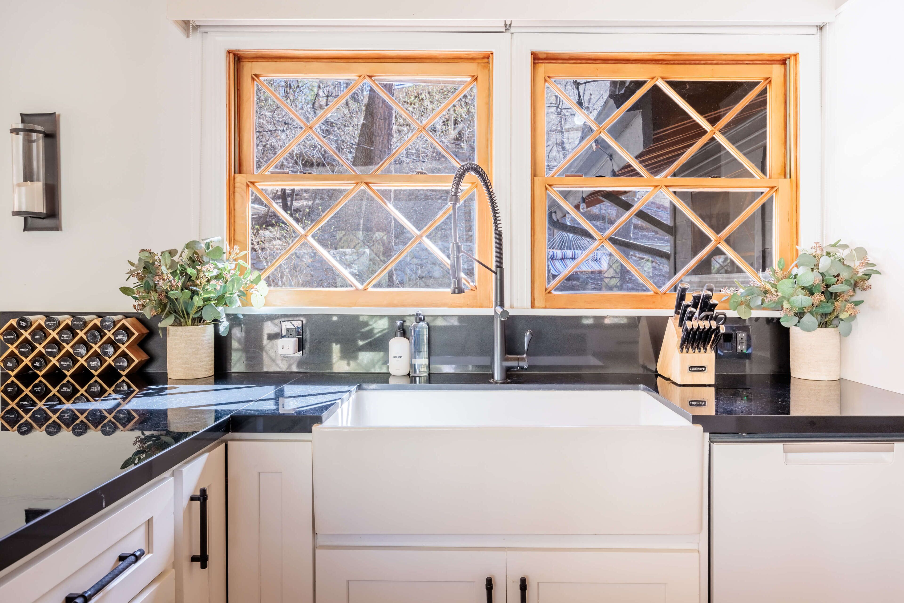 A kitchen with a double sink, wooden window frames, and a wine rack.