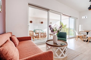 A modern living room with a sofa, a coffee table, and a dining area with chairs and a table. - Bright apartment with a large loggia and parking space, near downtown and the train station (Bègles)