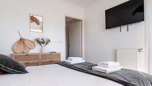 Ein Schlafzimmer mit einem Bett, einem Schminktisch, einem Spiegel, einem Flachbildfernseher und einem Heizkörper.