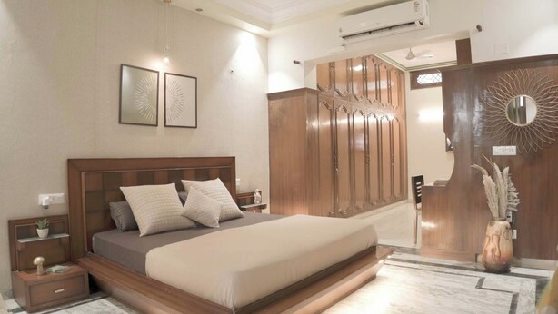 Un dormitorio con cama, mesitas de noche, armario y un espejo decorativo.