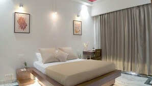 A modern bedroom with a large bed, two wall-mounted lights, and a large window with curtains.