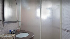 A bathroom with a sink, mirror, and shower.