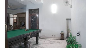 A room with a pool table, a door with a decorative glass panel, a ceiling fan, and a wall-mounted light fixture.