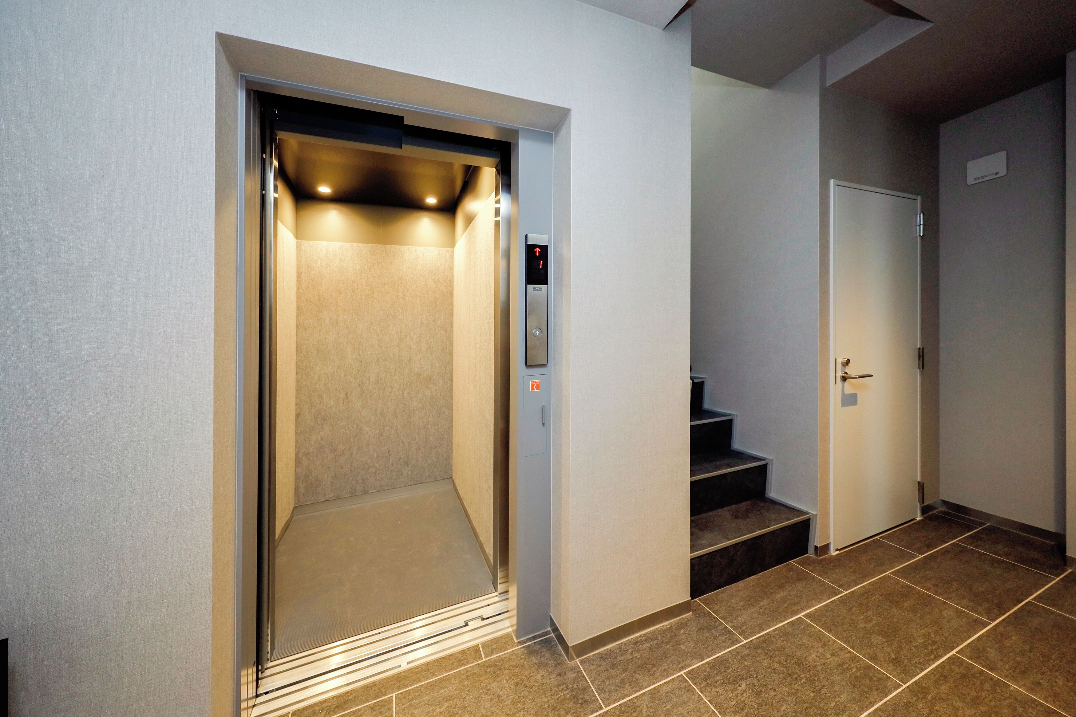 Een lift met bedieningspaneel en een deur.