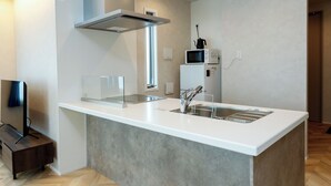 Une cuisine moderne dotée d’un grand îlot central, d’appareils électroménagers en acier inoxydable et d’un parquet en bois disposé en chevrons.