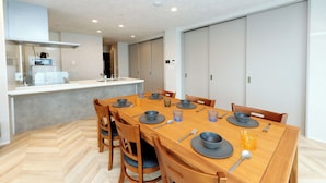Un espace repas moderne avec une table en bois dressée pour six personnes, agrémentée d’assiettes, de bols et de couverts.