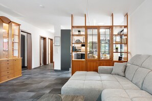 Ein modernes Wohnzimmer mit einer Eckcouch, Holzböden und einer Küche im Hintergrund.