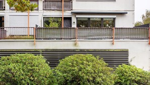 Un bâtiment moderne doté d’un balcon, de grandes fenêtres et d’une clôture en métal.