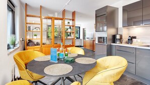 Une cuisine moderne avec un coin repas, comprenant une table ronde, des chaises jaunes et un meuble encastré.