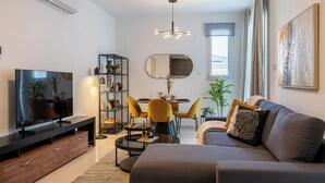 Un salon moderne comprenant un canapé, un téléviseur, une table à manger, des chaises et une bibliothèque.