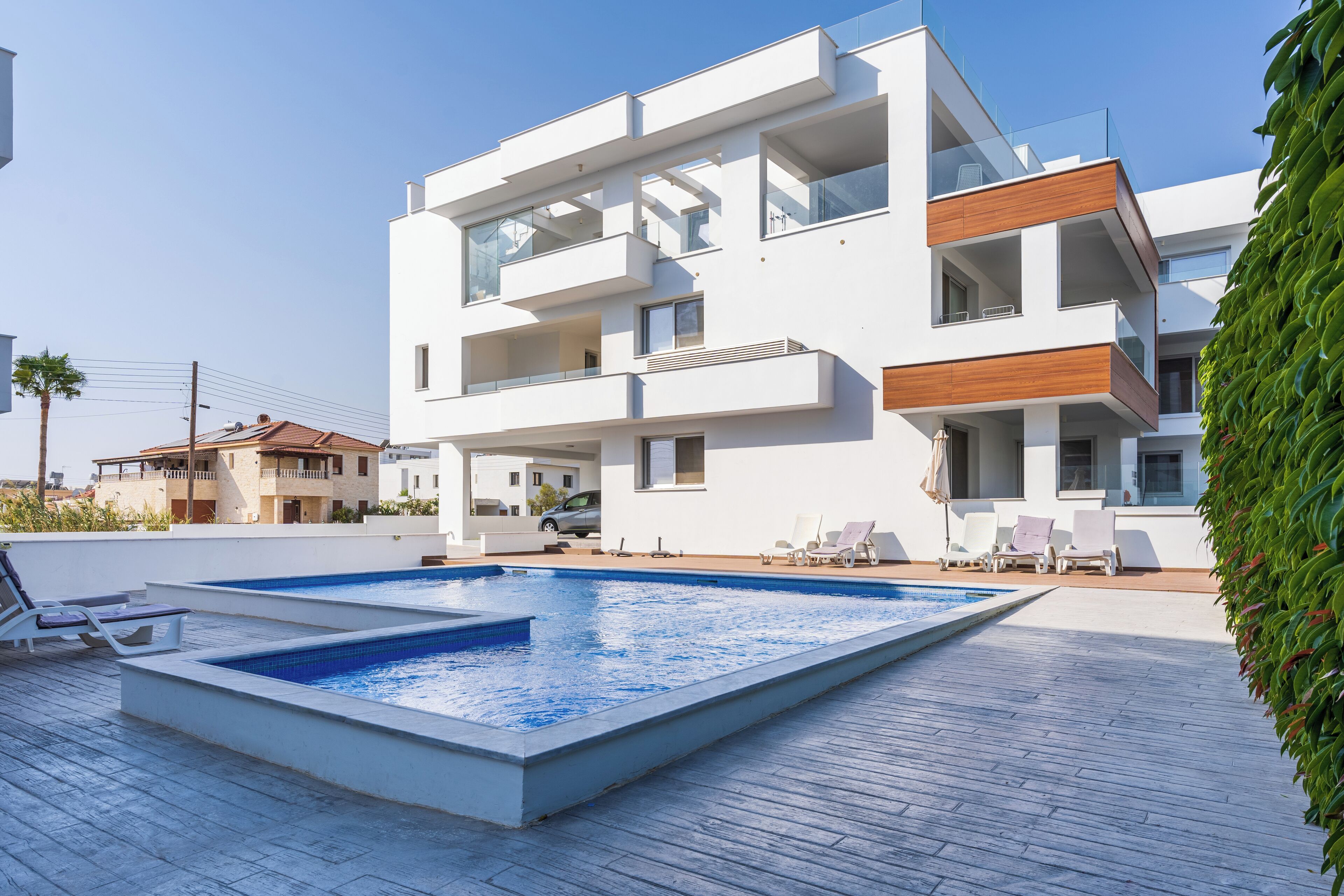 A modern two-story building with a swimming pool and outdoor seating.