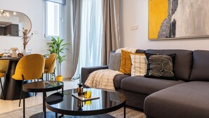 Un salon moderne avec un canapé, une table à manger et des chaises, ainsi qu’une table basse en verre.