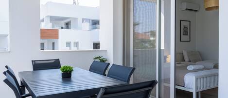 Uma varanda moderna com uma mesa de jantar, cadeiras e um vaso com planta.