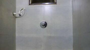 Un baño pequeño con baldosas, que incluye un inodoro, una ventana con reja de metal y un grifo instalado en la pared.