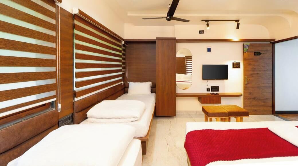 Una habitación de hotel con cama, escritorio, televisor y ventilador de techo.