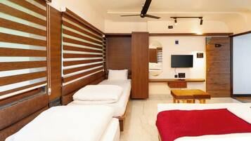 Una habitación de hotel con cama, escritorio, televisor y ventilador de techo.